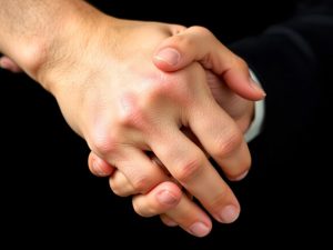 Mână strângând o altă mână în semn de solidaritate.